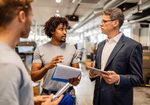 mid-adult-engineer-using-touchpad-communicating-with-african-american-worker-about-product-reports-industrial-building_637285-4098